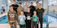 Групповое фото юных пловцов и тренера у крытого бассейна; двое детей спереди держат грамоты. - 168.Ru