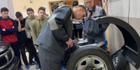Школьники и студенты в рабочей форме вокруг автослесарного станка с колесом — демонстрация в мастерской - 168.Ru