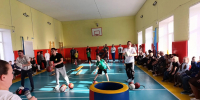 Внутренний школьный спортивный зал: папы и дети участвуют в эстафетах, снаряды и сидящие зрители вдоль стены - 168.Ru