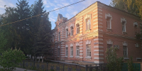 Старое кирпичное здание районного суда за оградой, вечернее солнце на фасаде - Newsroom24.Ru