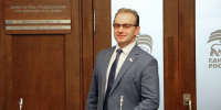 Мужчина в деловом костюме и очках стоит в кабинете у деревянной двери с табличкой «ЗАМЕСТИТЕЛЬ ПРЕДСЕДАТЕЛЯ ГОСУДАРСТВЕННОЙ ДУМЫ»; на стекле виден логотип «ЕДИНАЯ РОССИЯ». - 168.Ru