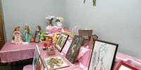 На фото — выставка декоративно‑прикладного творчества: на столах с розовыми скатертями расставлены куклы, картины в рамках, плетёные корзины, цветочные композиции и другие рукодельные изделия. - Коркинский муниципальный округ