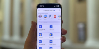На фото - В руке держат смартфон с открытым приложением для Челябинской области — на экране видны категории сервисов (от «Управляющие компании» до «Бизнес») и блок «Официальные каналы». - Коркинский муниципальный округ