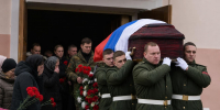 Военные несут гроб, покрытый российским флагом; рядом скорбящие люди с цветами и венком. - 168.Ru