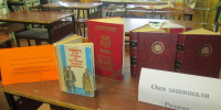 Книжная выставка в библиотеке: книги на столах и стеллажи на заднем плане - 168.Ru
