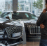 Мужчина осматривает два чёрных премиальных автомобиля в автосалоне. - 168.Ru