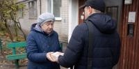 Пожилая женщина передаёт пачку наличных денег мужчине у подъезда многоквартирного дома. - 168.Ru