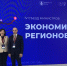 На изображении двое людей стоят на фоне синего баннера с текстом. Текст сообщает о съезде министров экономики регионов в Москве., Изображение. - Минэкономразвития
