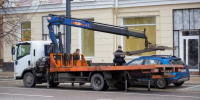 Эвакуатор на городской улице загружает легковой автомобиль на платформу - 168.Ru