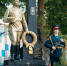 На фото — памятник Героям Советского Союза — выпускникам системы ПТО с бронзовой фигурой воина, венком и памятными надписями; по бокам — часовые в форме с автоматами на фоне деревьев и здания. - Министерство образования и науки