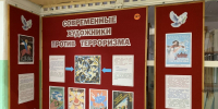 Красный художественно-информационный стенд с заголовком «СОВРЕМЕННЫЕ ХУДОЖНИКИ ПРОТИВ ТЕРРОРИЗМА», на борде размещены плакаты, текстовые листы и декоративные изображения (голуби). - 168.Ru