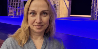 Женщина у сцены в театре; на заднем плане видны декорации и реквизит. - 168.Ru
